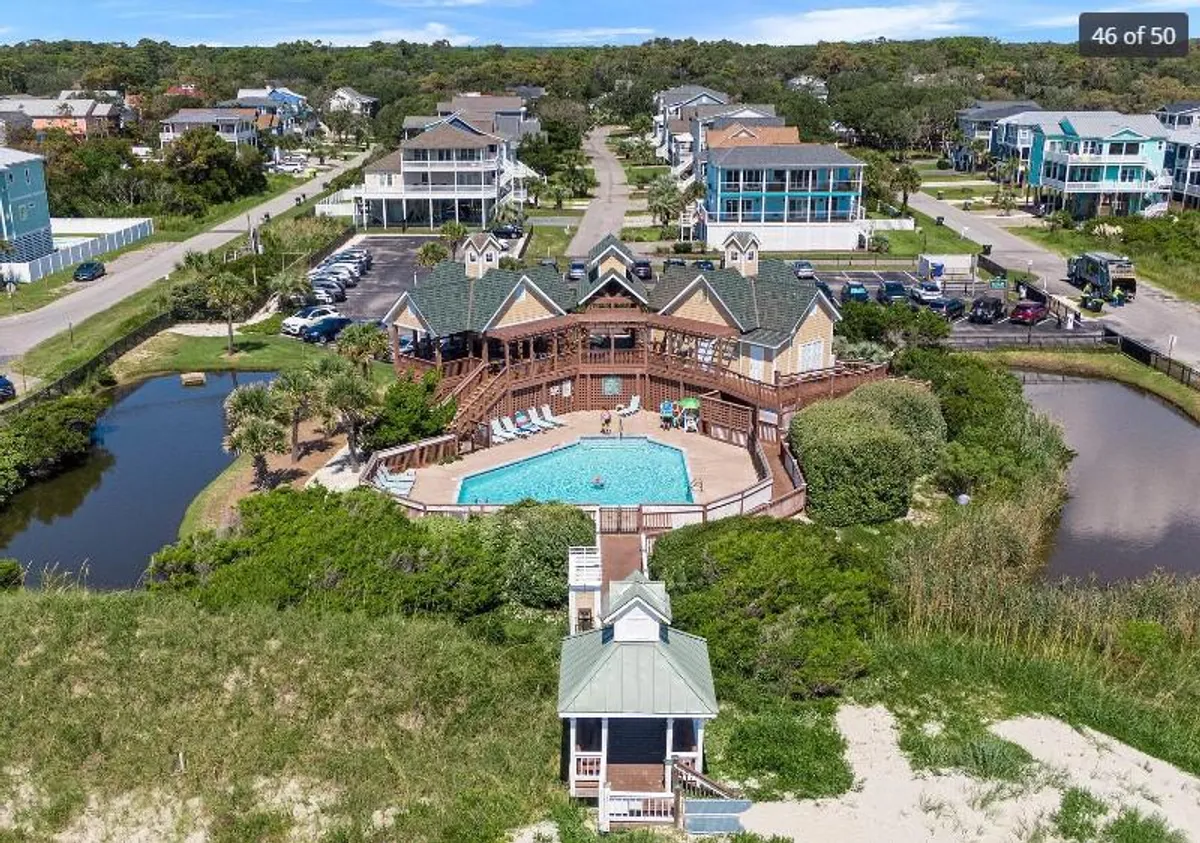 A vibrant scene featuring a swimming pool with surrounding greenery, nearby houses, and direct beach access. The atmosphere is both lively and relaxing, highlighting opportunities for swimming, social gatherings, and water-related activities.