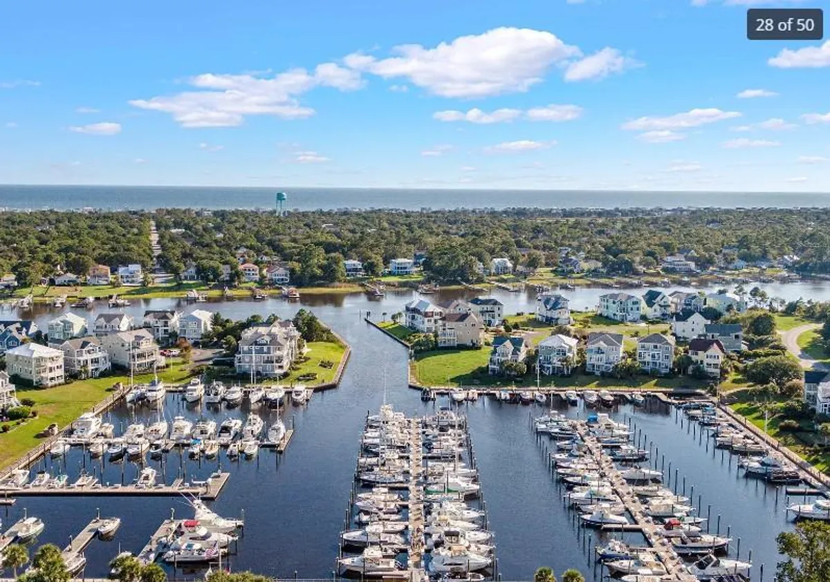 A picturesque marina with boats docked along the waterway, residential homes in the background, and a peaceful atmosphere ideal for boating, fishing, or a stroll along the waterfront.