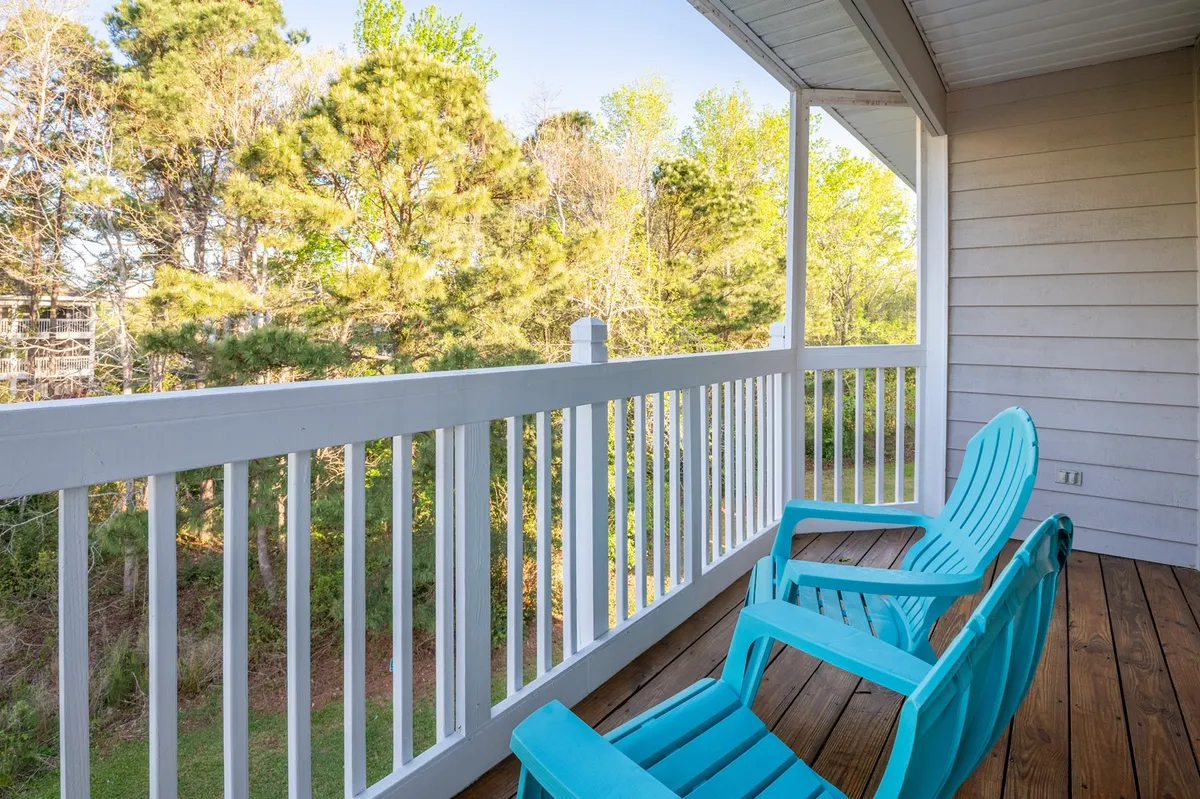 Turquoise chairs arranged on a wooden deck overlooking green trees, suggesting a perfect spot for sunset views, watching wildlife, or stargazing at night. The tranquil setting evokes relaxation and exclusivity.