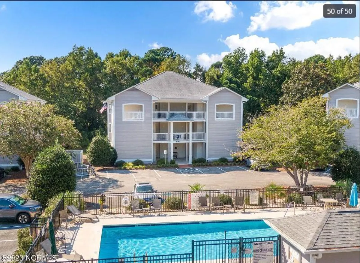 The image showcases a sparkling swimming pool surrounded by a well-maintained landscaped garden, with the modern condo building as a backdrop. Lounge chairs invite guests to relax poolside, while the warm glow of sunset adds a tranquil atmosphere ideal for unwinding or socializing.